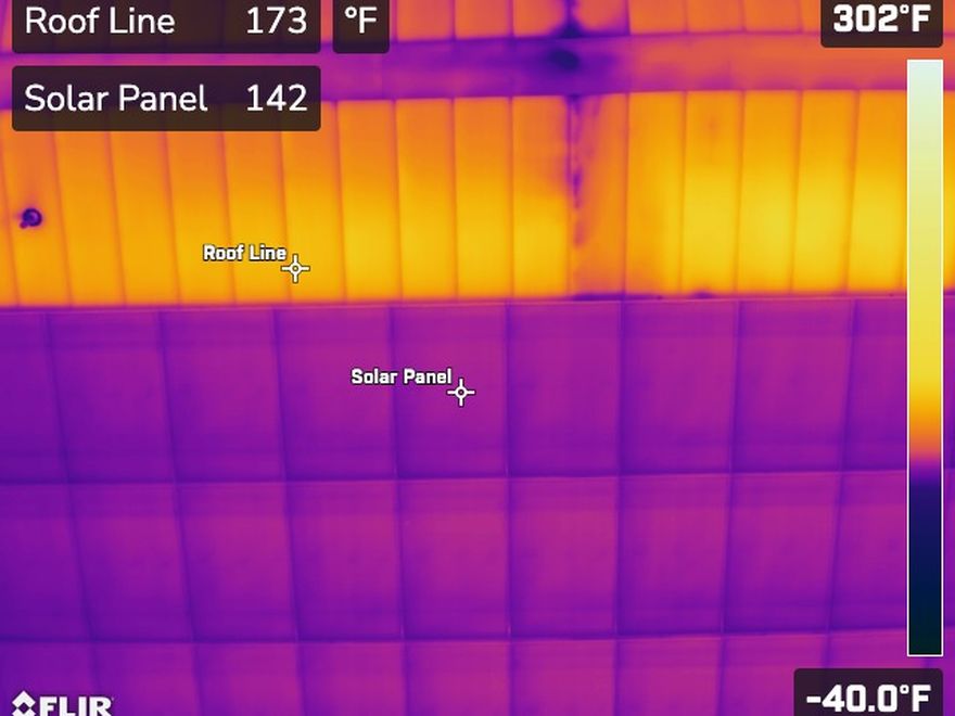 Radiometric thermal image with spot temperature measurements on a roof line and solar panel